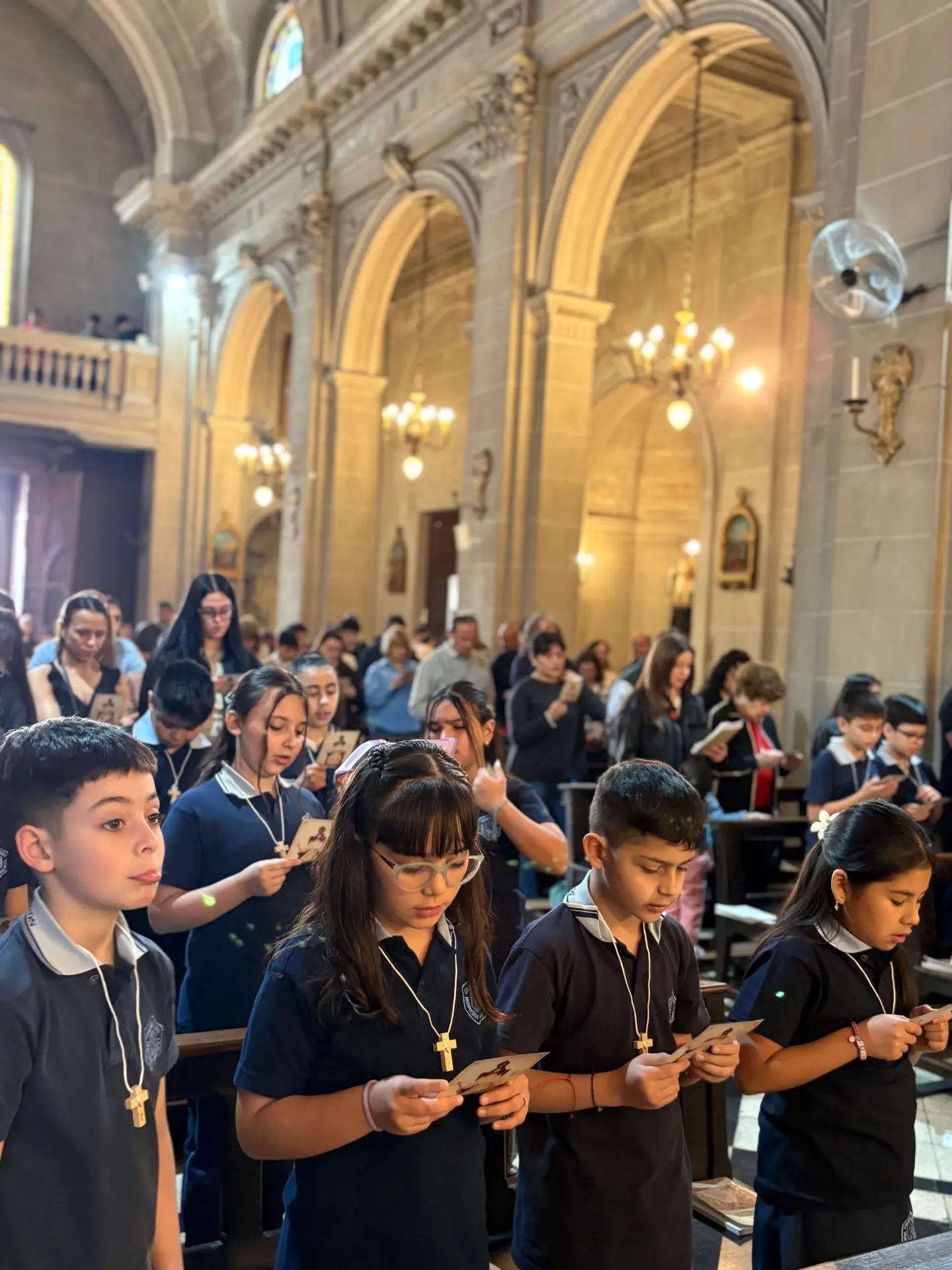 Alumnos del colegio rezando con estampas durante la celebración